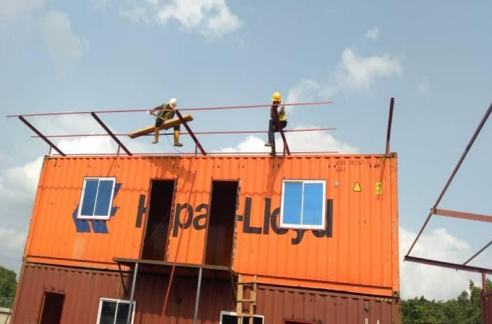 Workers fitting roof steel on containers